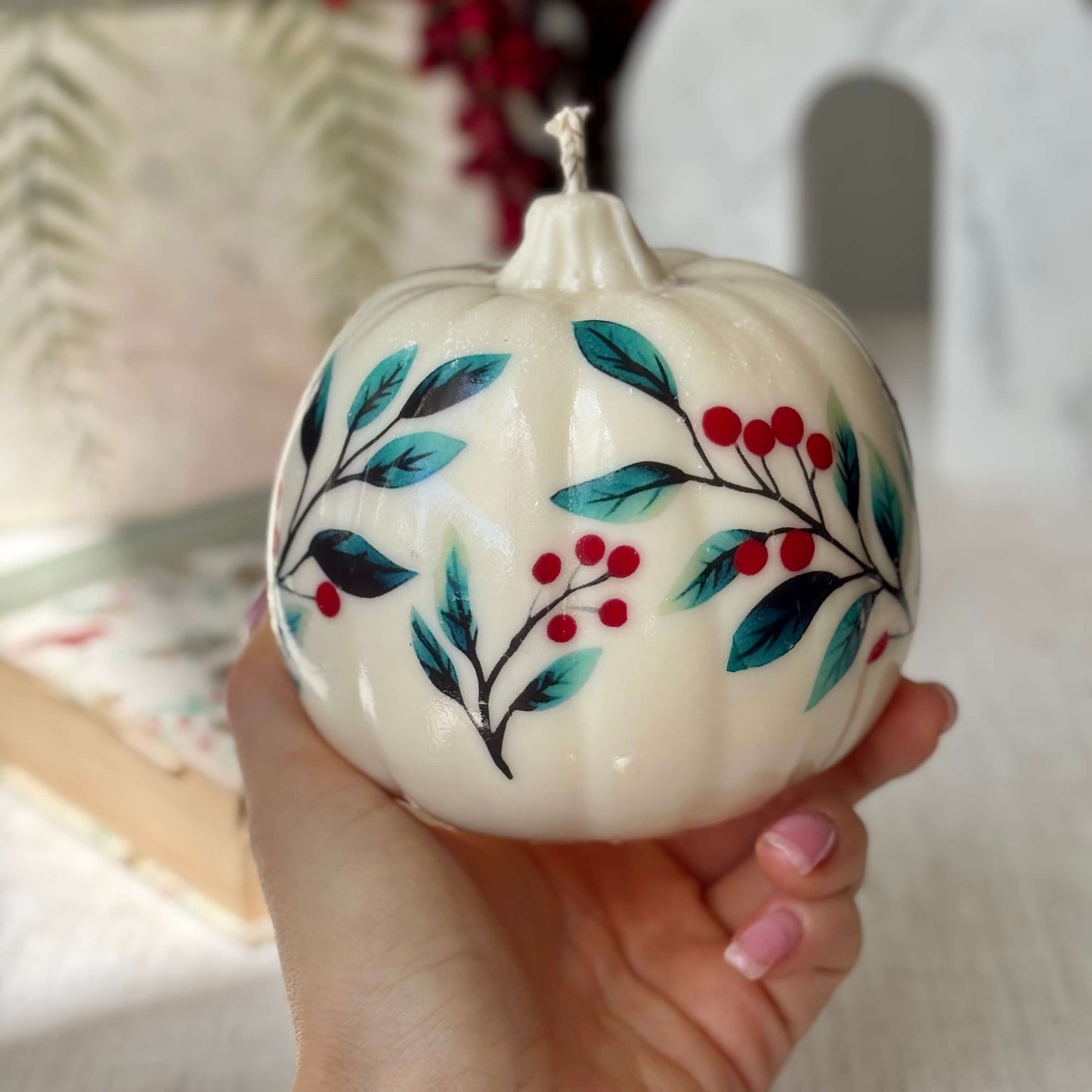 Artisan pumpkin candle with blue leaves and red berries, shown in hand for size reference — great handmade gift for Halloween, birthday, Thanksgiving or fall home styling