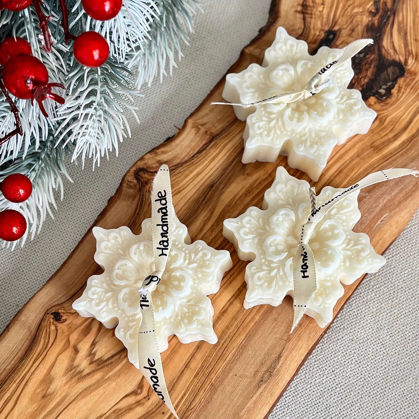 Winter snowflake shaped candles in natural soy wax with festive greenery background