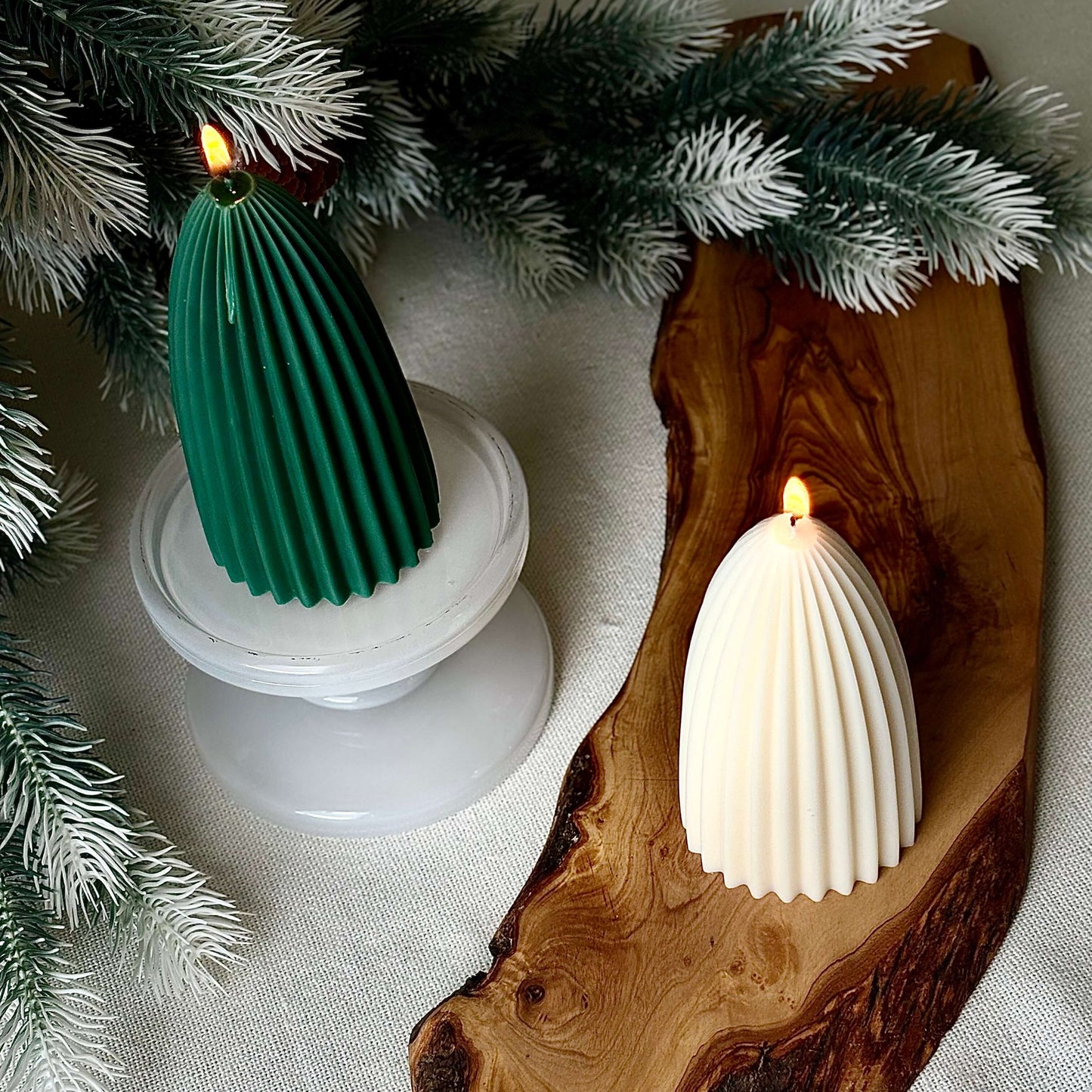 Green ribbed soy wax candle on pedestal with ivory tree candle, festive Christmas décor setting