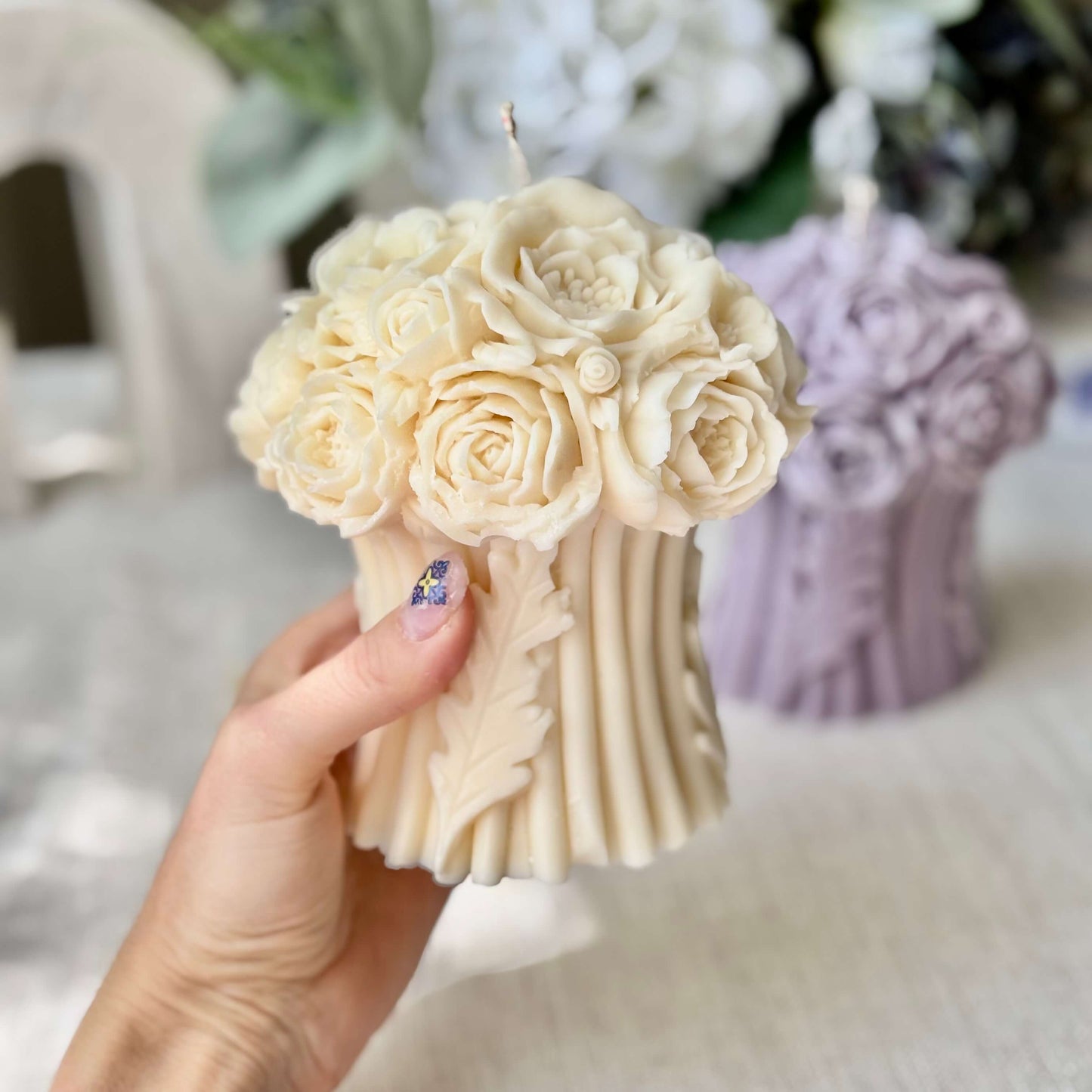 Hand holding an ivory peony bouquet candle, handmade from soy wax, floral sculptural candle, wedding table decoration, artisanal home decor gift.