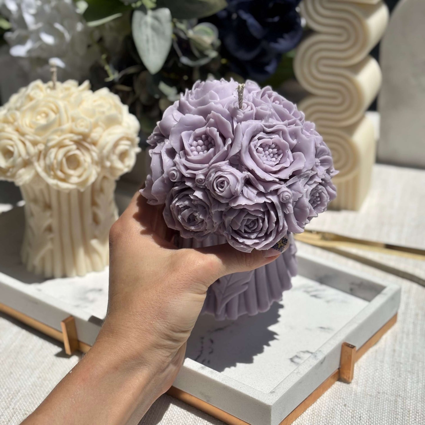 Hand holding a lavender peony bouquet candle, handmade from soy wax, floral sculpture for home decor, wedding gift candle.