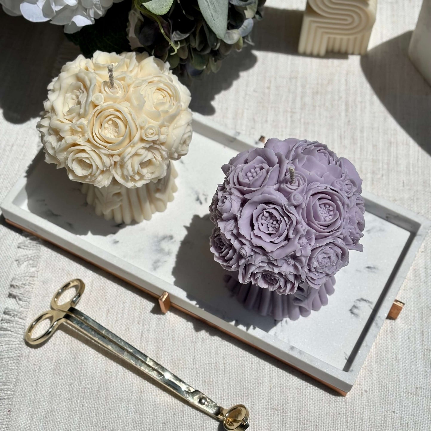 Two handmade peony bouquet candles on a marble tray, purple and ivory sculptural soy wax, floral wedding decor, romantic home accents.