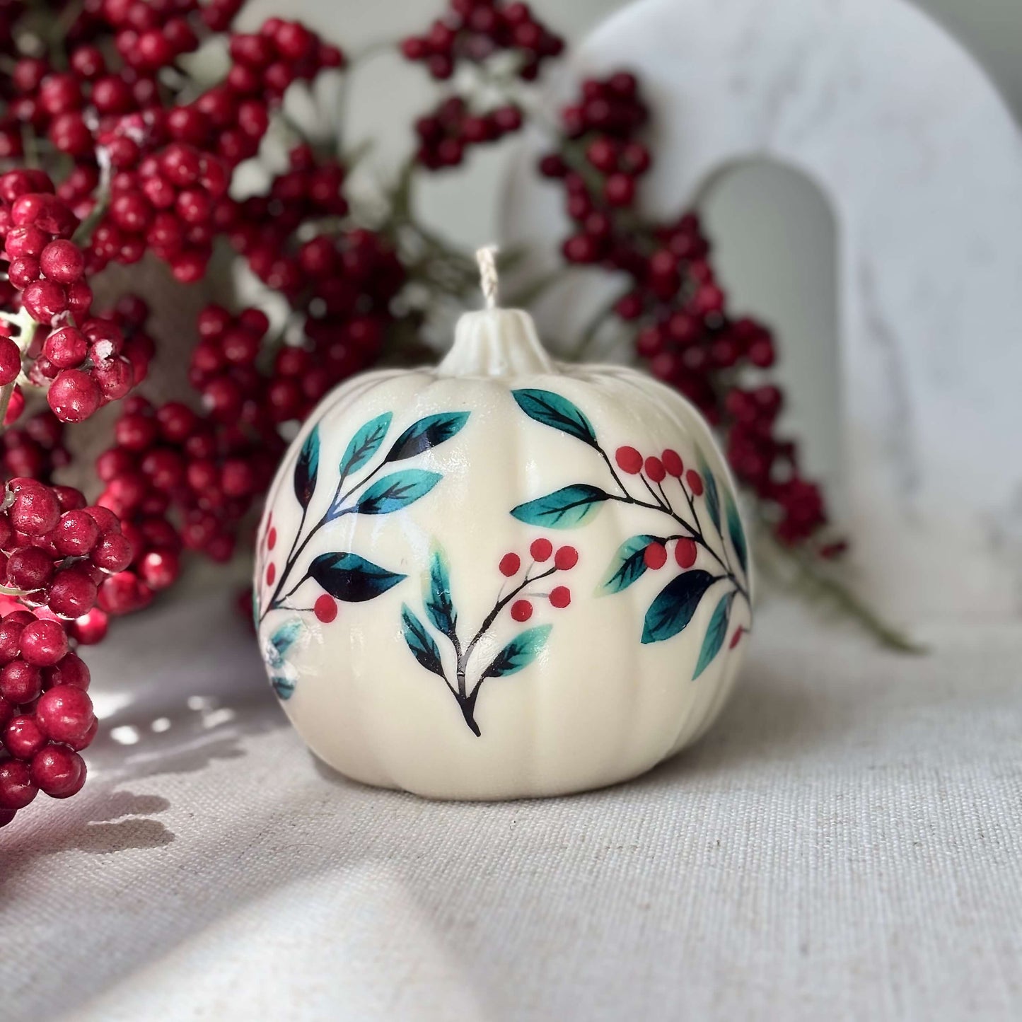 Creamy white pumpkin candle with vintage floral and red berry accents, surrounded by festive winter berries — perfect for Thanksgiving, Halloween, Mother’s Day or as a Christmas centerpiece