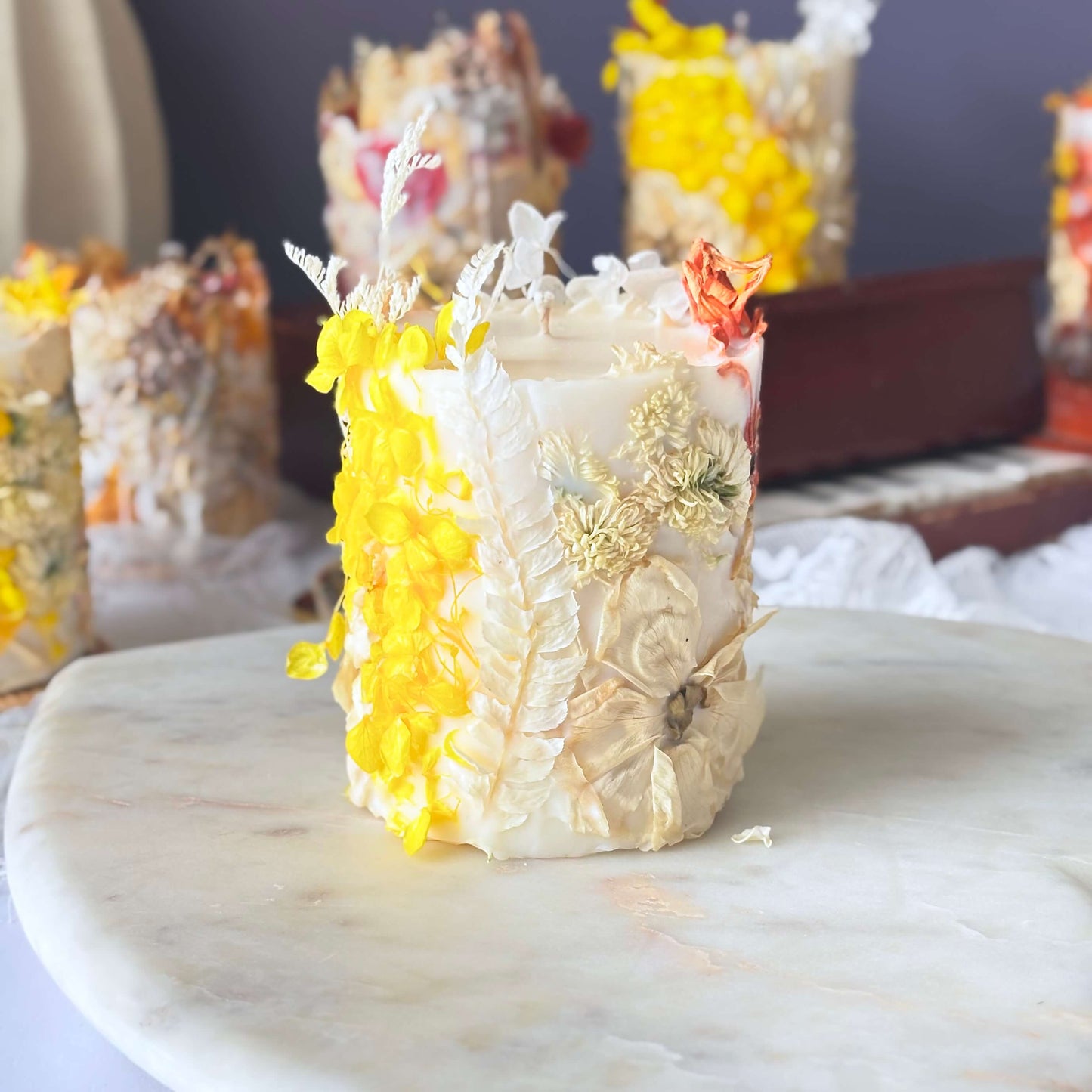Handmade botanical pillar soy candle with dried yellow flowers and delicate natural decor, perfect as a gift or home accent