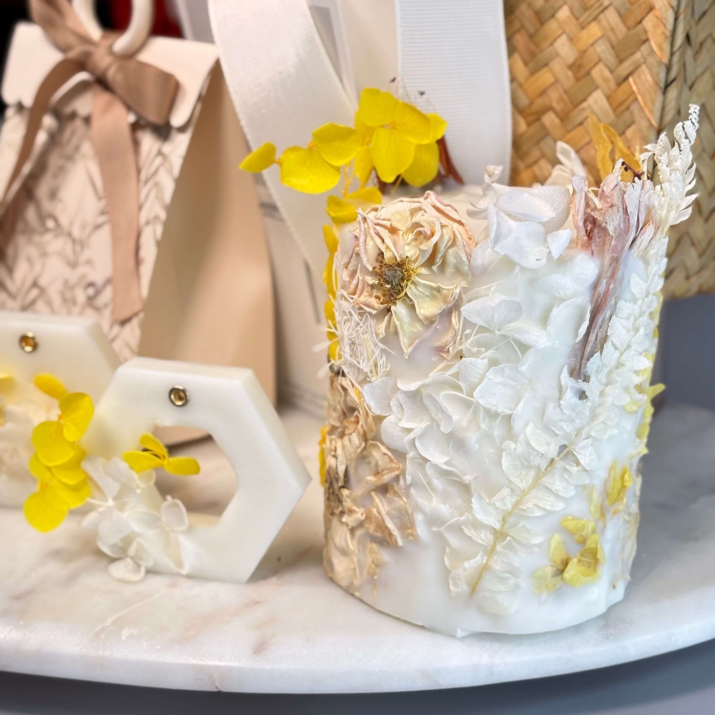 Close-up of handcrafted soy candle with dried flowers and yellow petals on a heart-shaped tray