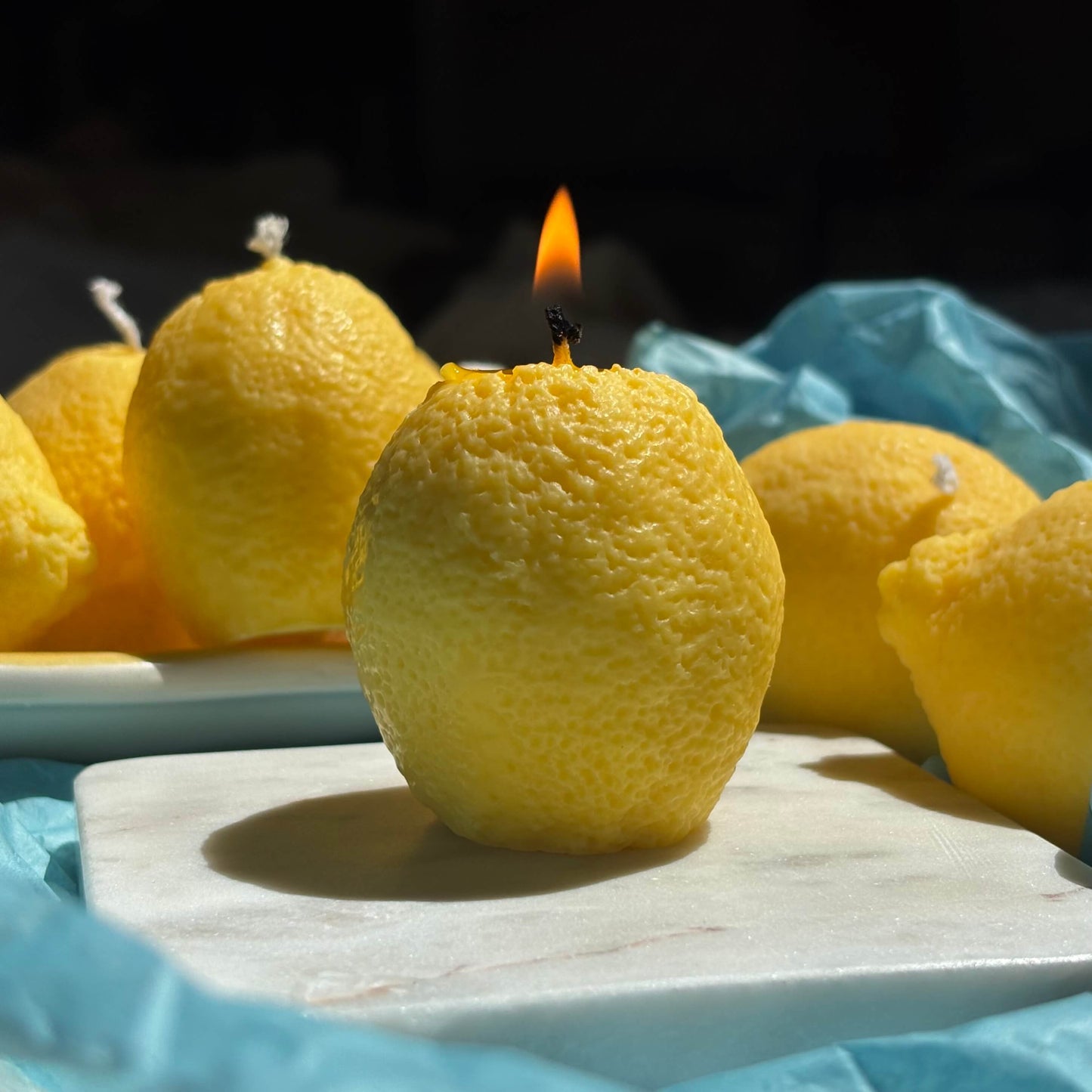 Close-up of burning lemon candle made of soy wax. Realistic fruit candle shown lit for display.