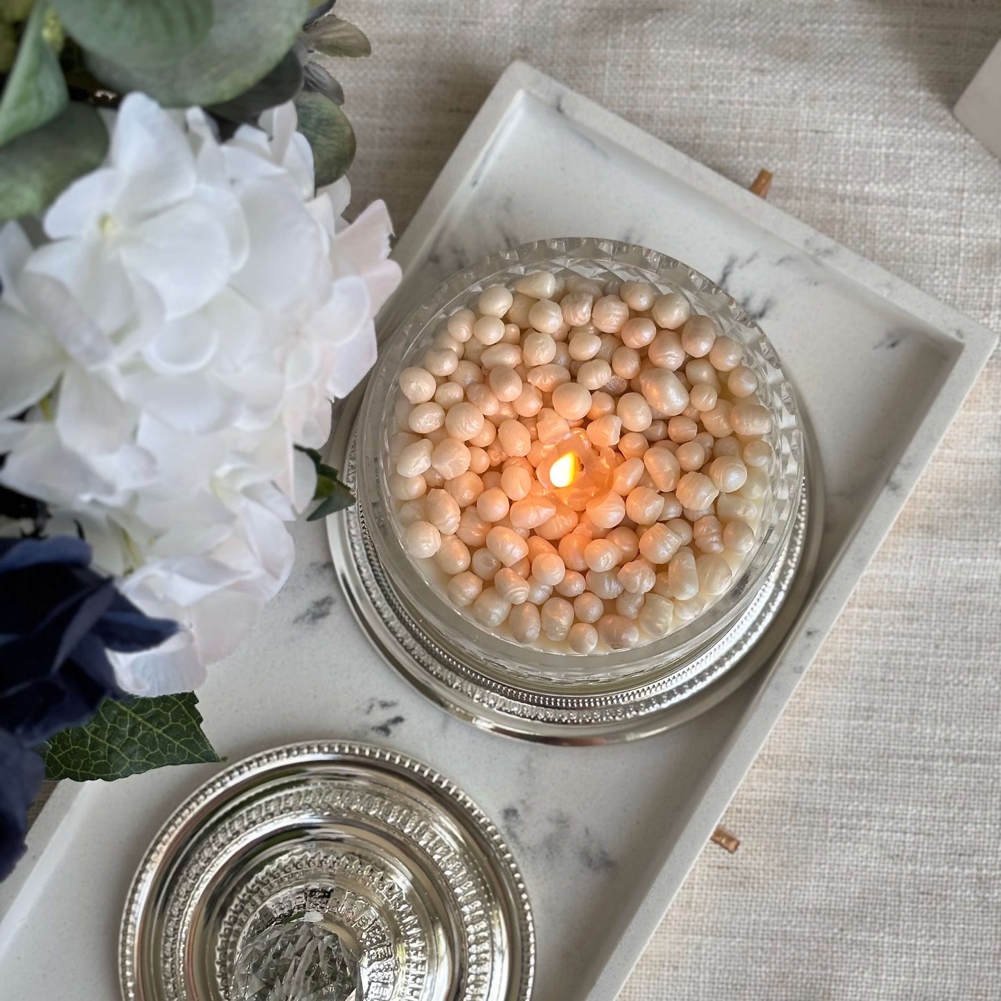 Burning pearl candle surrounded by flowers — luxury wedding gift and elegant décor for any interior