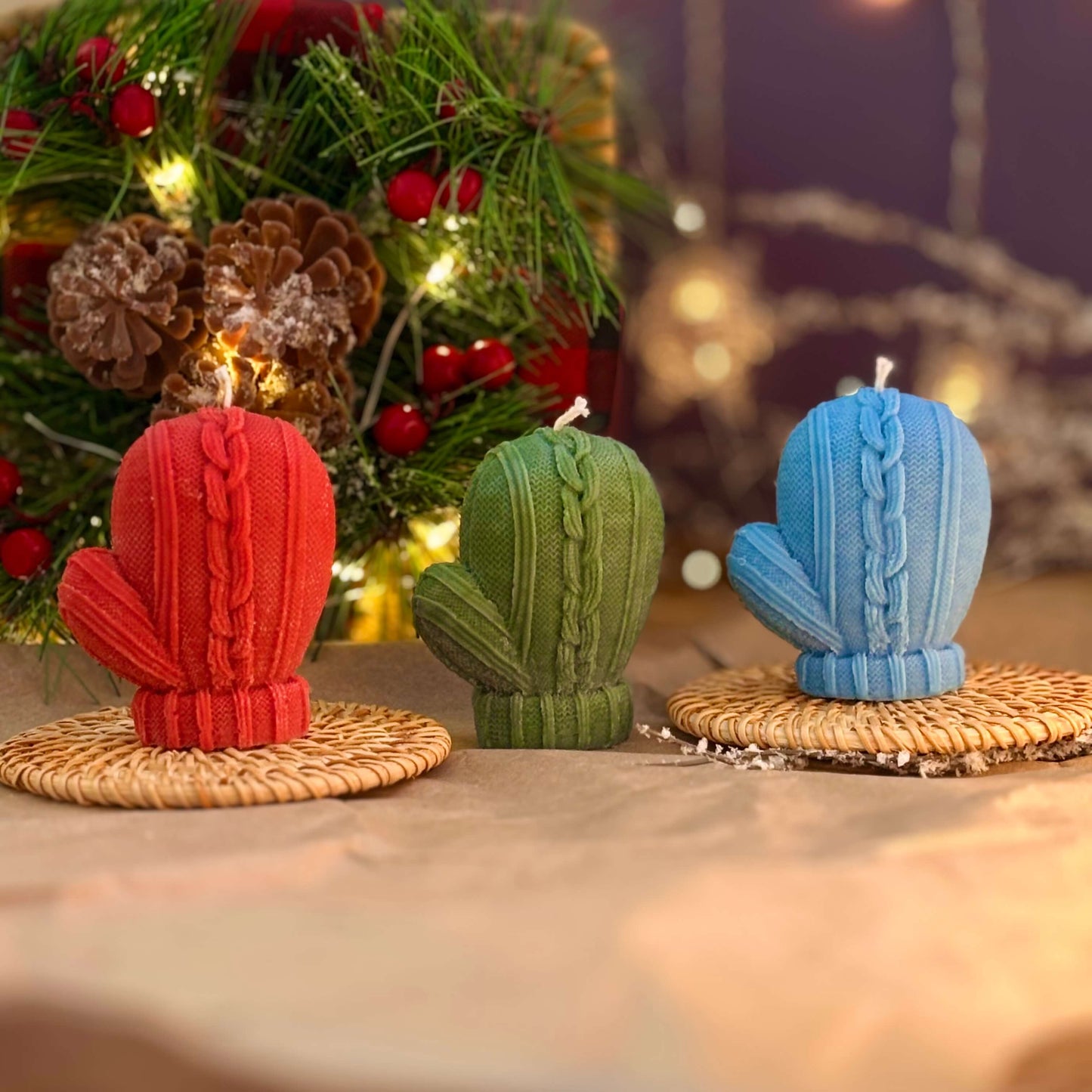 Festive red green and blue mitten candles on rattan pads for Christmas gift or home decor