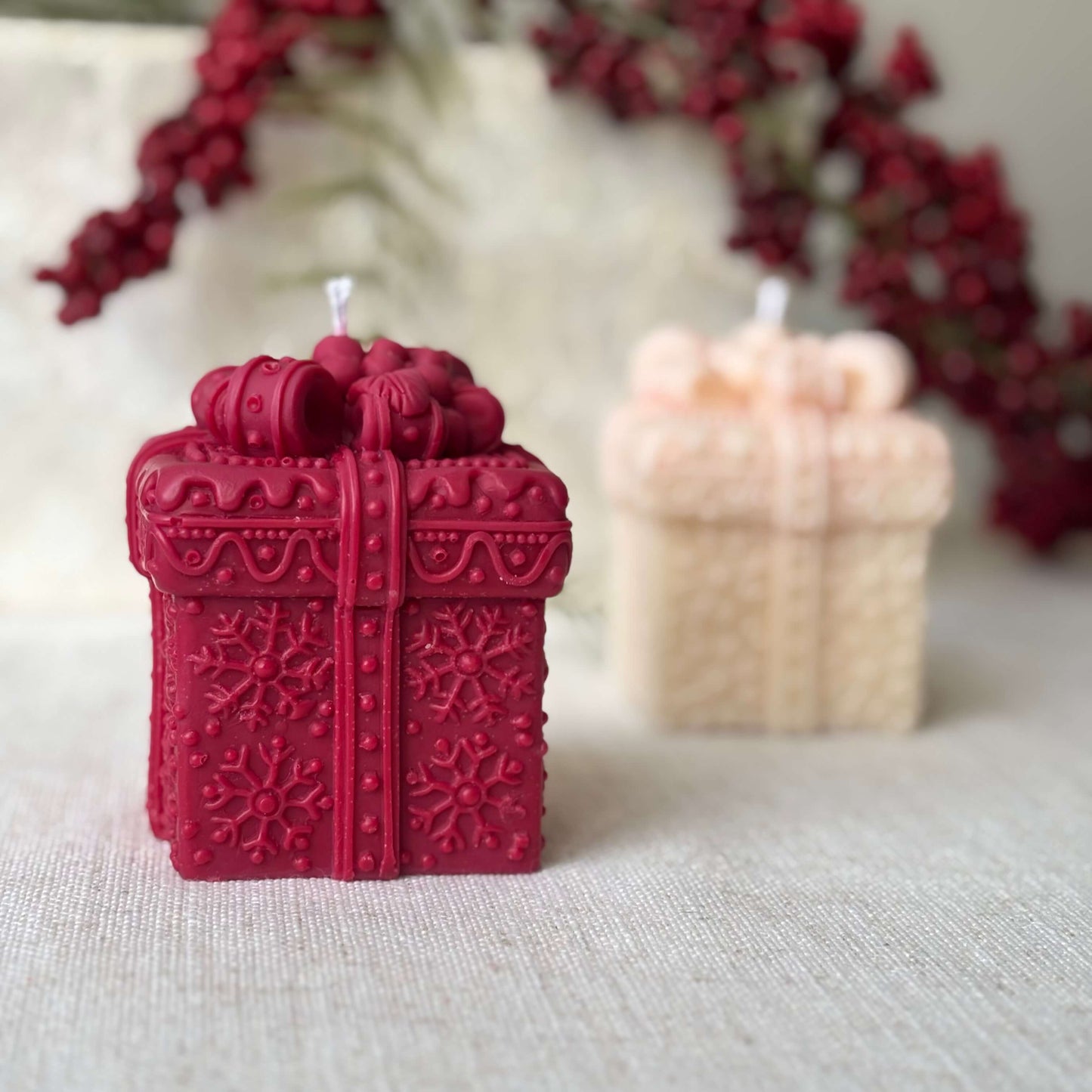 Handmade red soy candle shaped like a festive gift box, holiday berries decor.