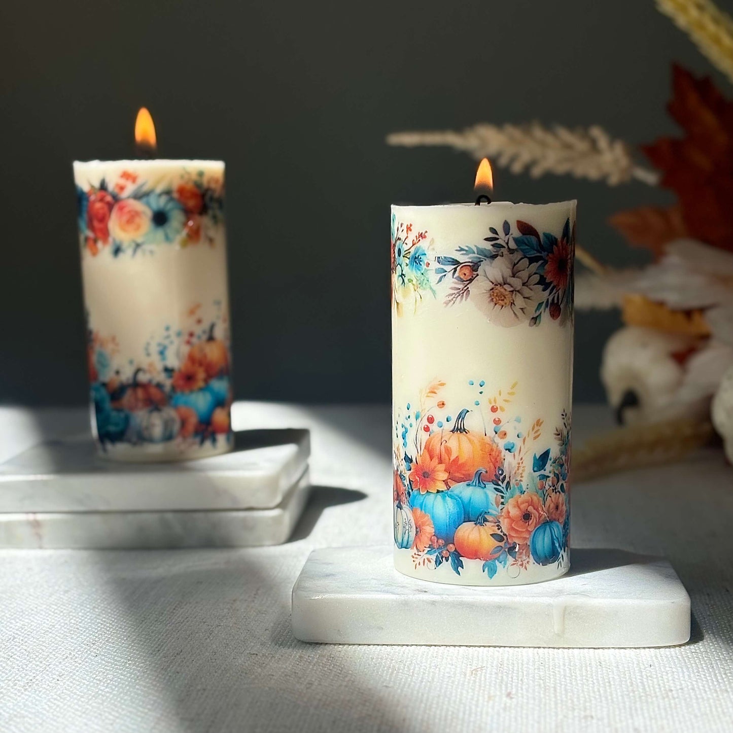 Diamond glossy pumpkin candles glowing with autumn floral design on marble base