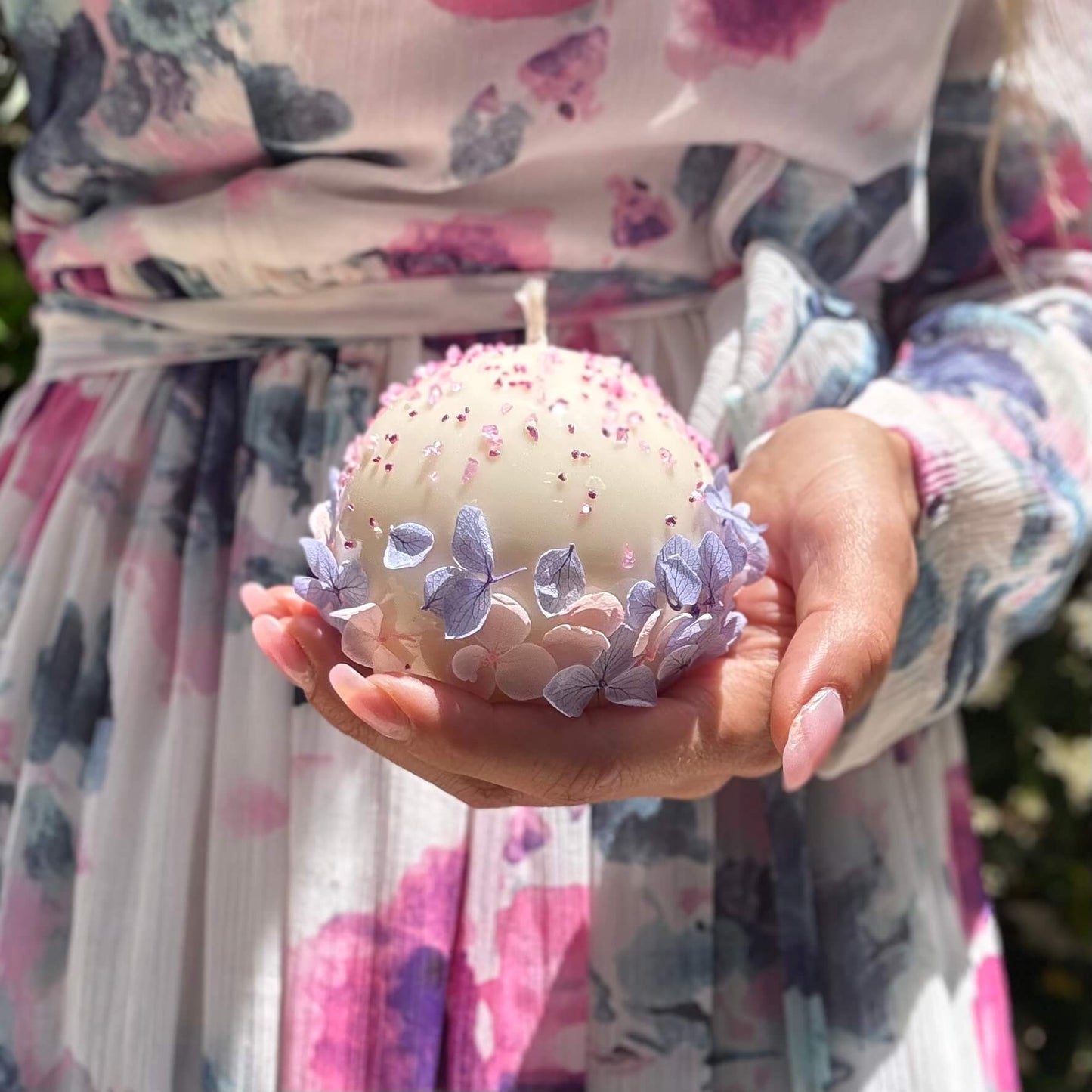 Round handmade floral candle with hydrangea petals held in hands, elegant gift for women