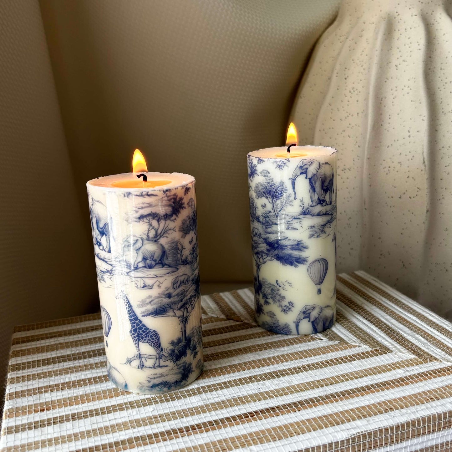 Glossy hand-poured candles featuring giraffe and elephant illustrations, burning softly on striped surface, ideal for cozy coffee table setup.
