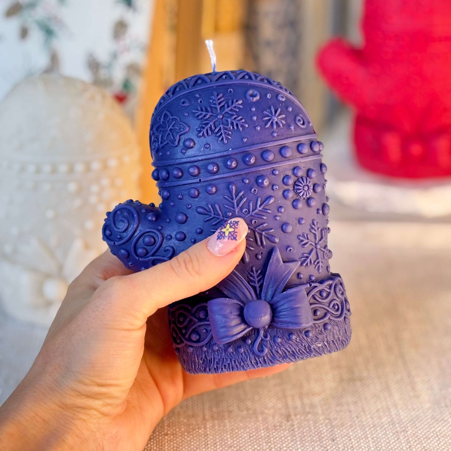 Hand holding a deep blue mitten candle with intricate snowflake design — soy wax, premium fragrance oils, Christmas gift for her.