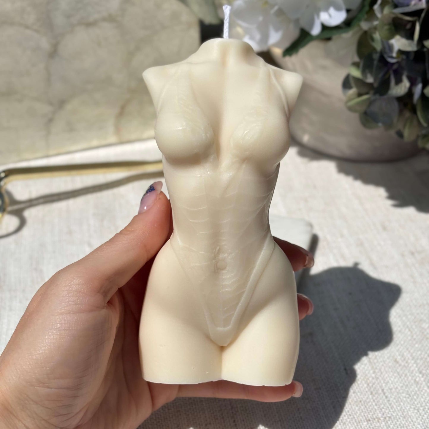 Hand holding a white female torso candle, handmade soy wax sculpture, aesthetic decorative gift accent.
