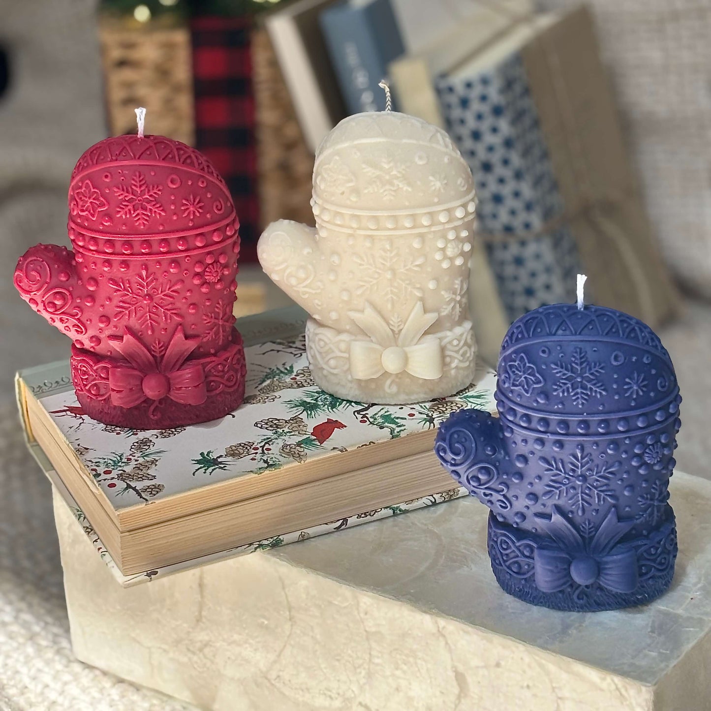 Three festive mitten candles in red, white, and blue on a decorative book — perfect Christmas gift, Thanksgiving table accent, handmade soy wax.