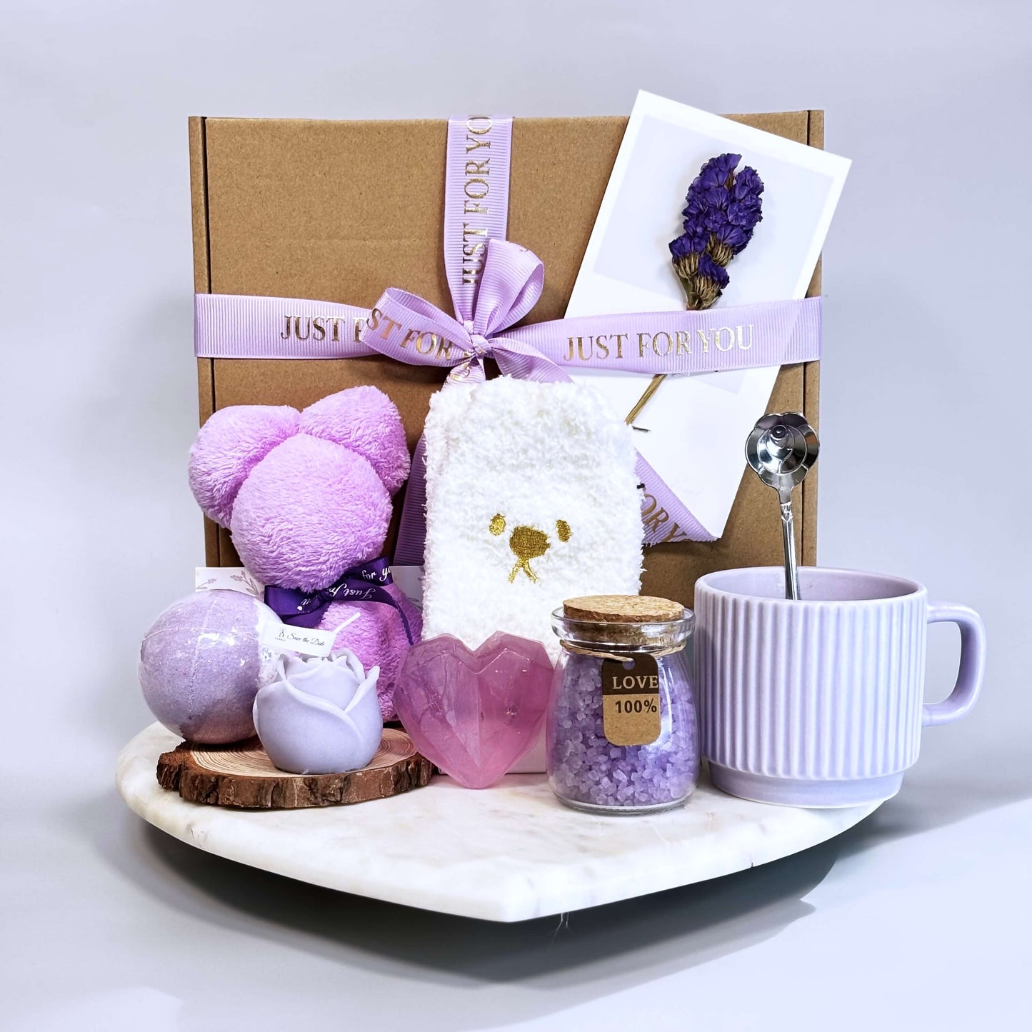 Lavender gift box with ceramic mug, bath bomb, candle, heart soap, cozy socks, and spa accessories in purple theme