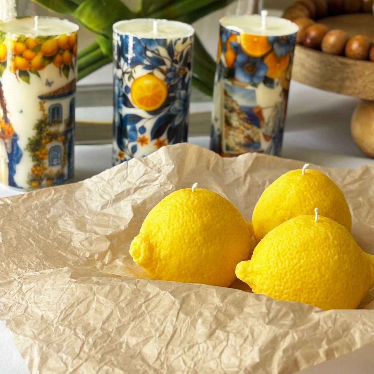 Three lemon candles on craft paper with botanical candles in background. Citrus decor concept.