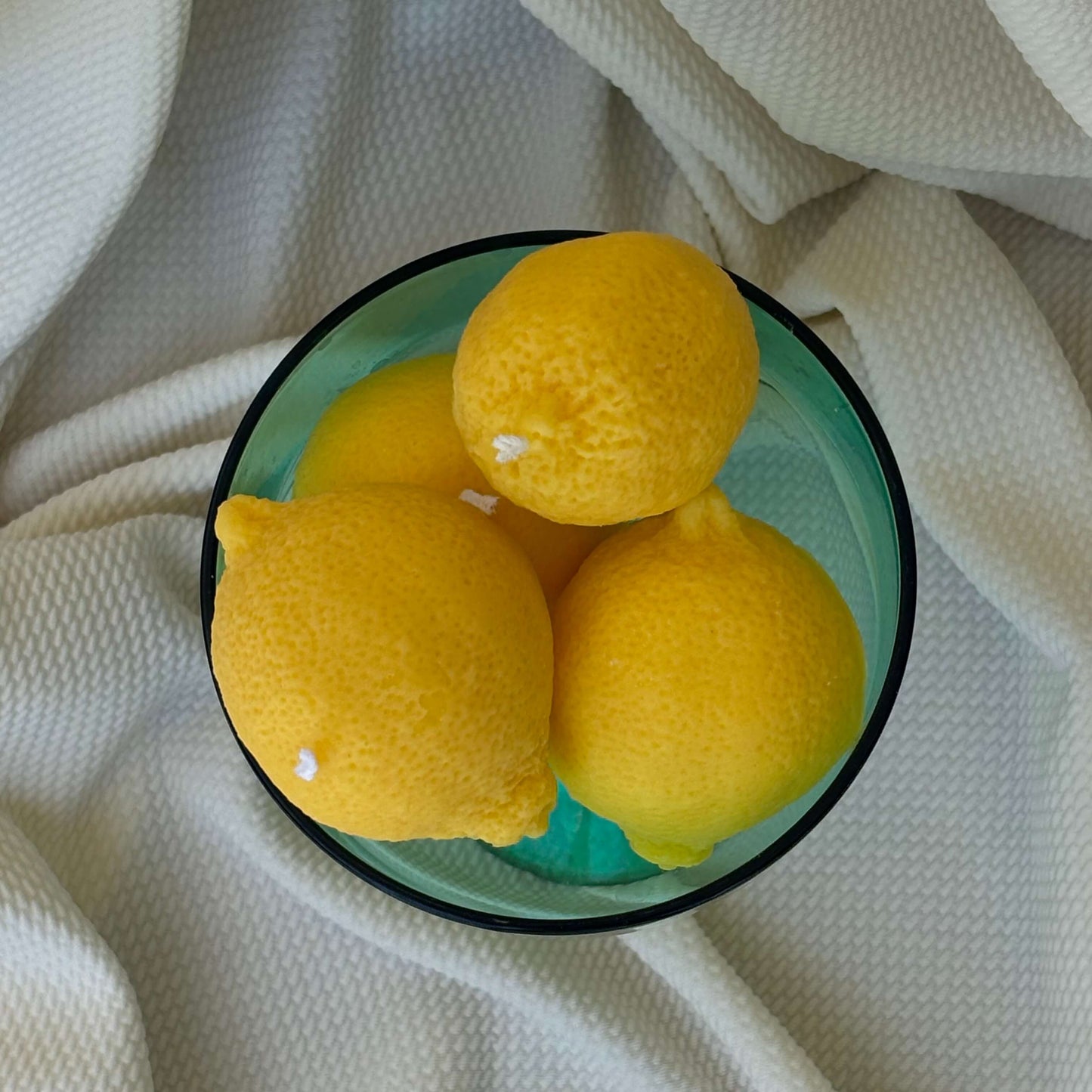 Top view of soy wax lemon candles arranged in a glass dish. Handmade fruit candles for home decor.