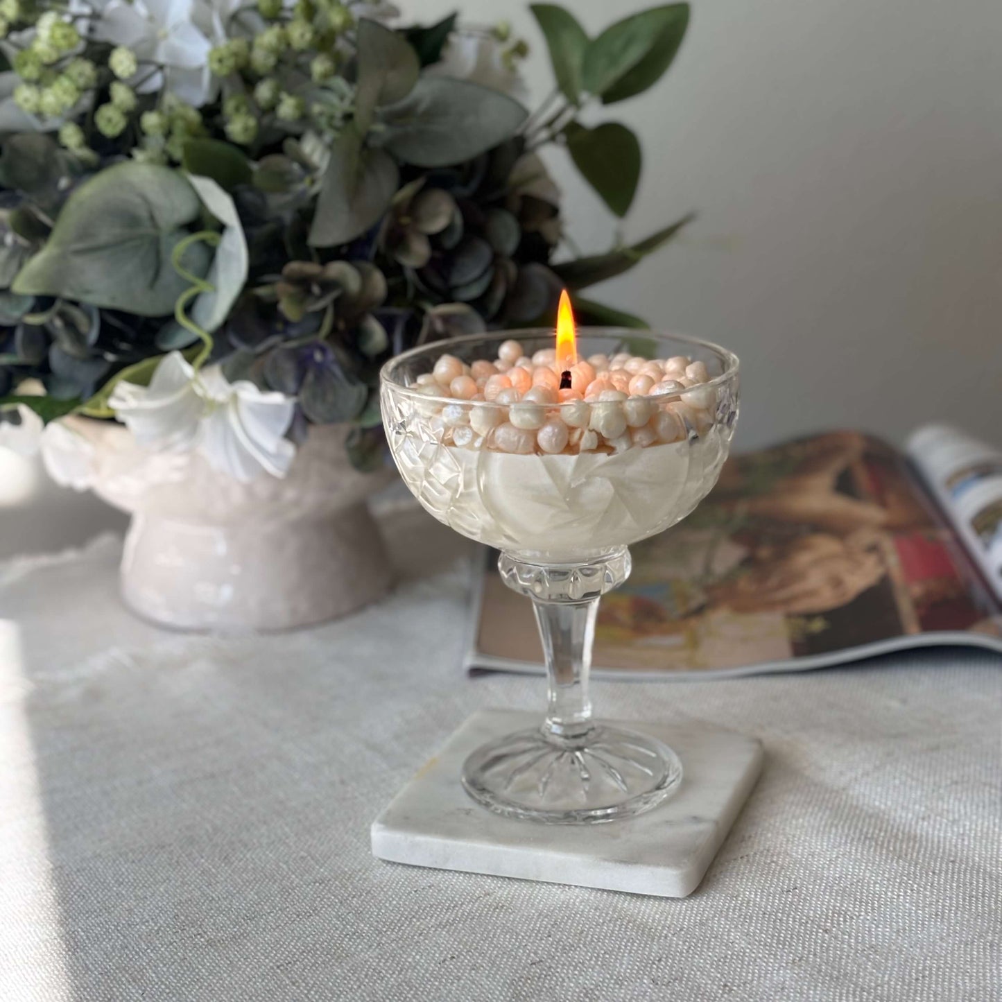 Soy wax pearl candle burning in glass coupe — romantic floral home décor