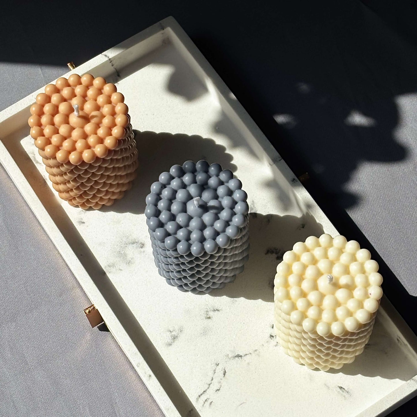 Elegant trio of artisan wax candles in ivory, slate blue, and latte, styled for minimal decor or thoughtful gifting.