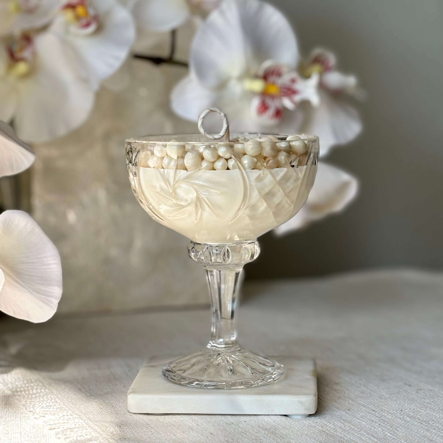 Elegant soy wax pearl candle in glass coupe with orchids — perfect wedding or anniversary décor