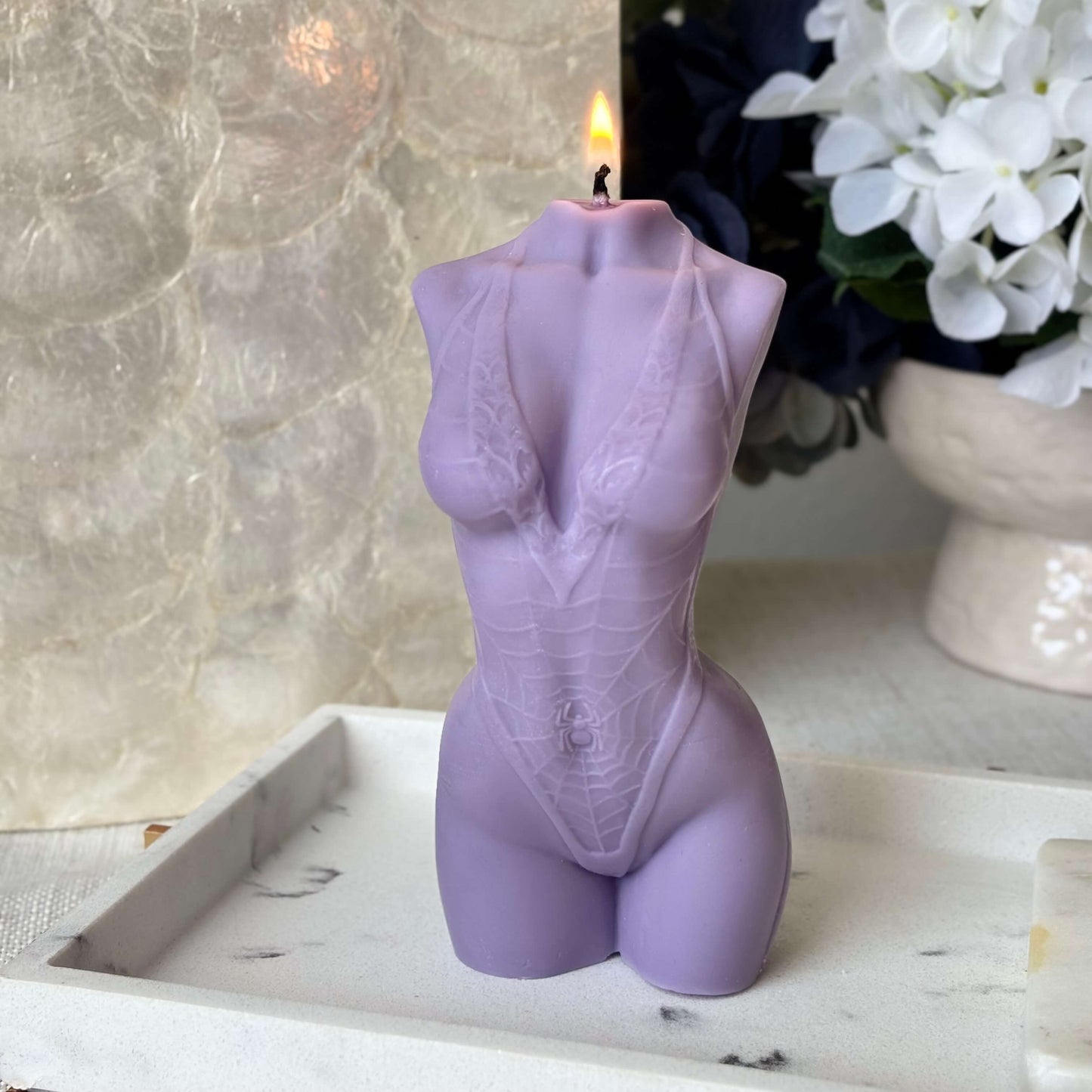 Purple female torso candle lit, handmade soy wax sculpture decorative accent with elegant background.