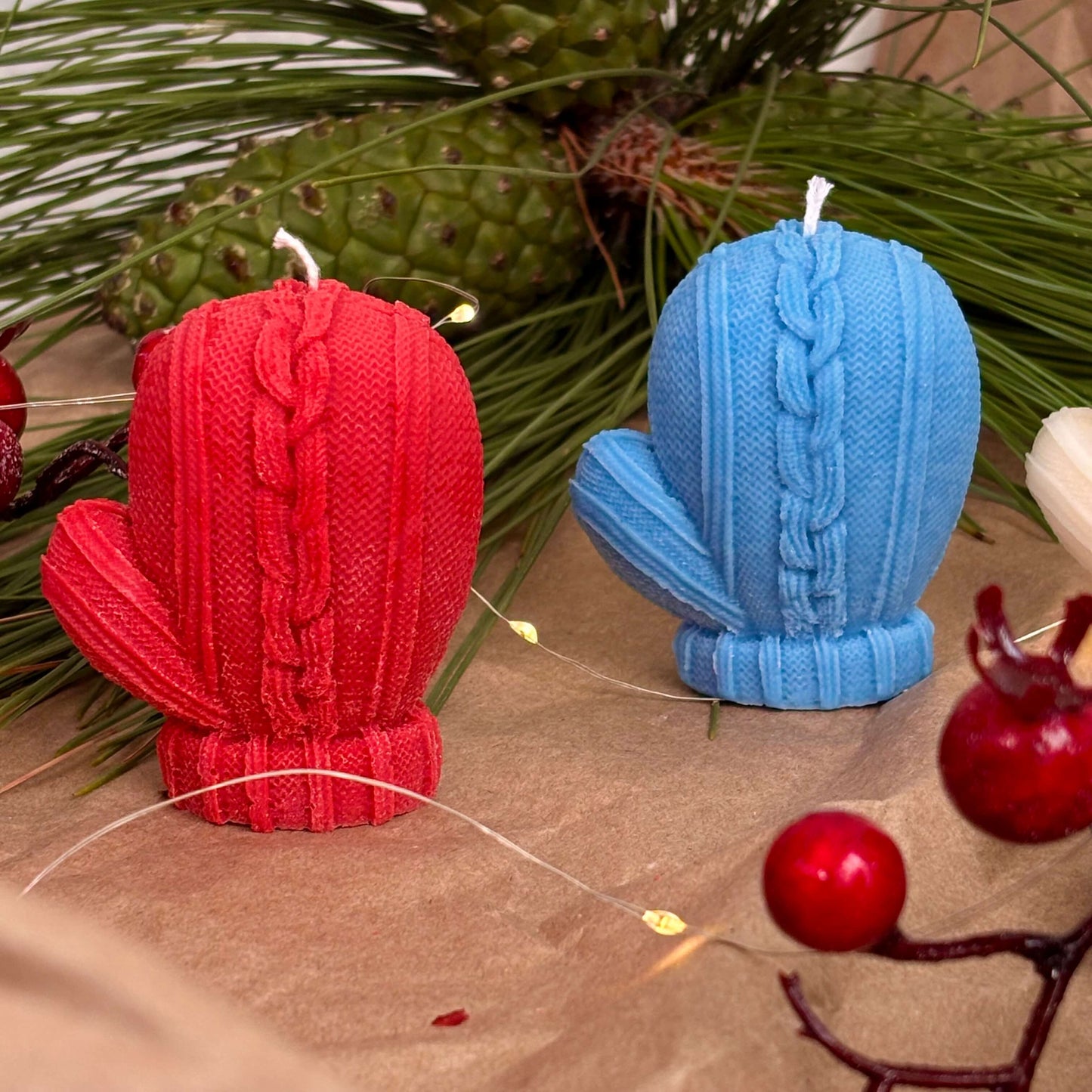 Red and blue mitten candles for festive gift or Christmas table decoration with pine and berries