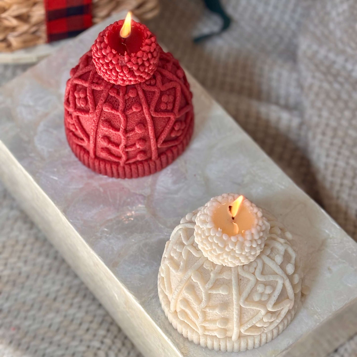 Two soy wax hat candles in red and ivory gently burning on a marble platform, styled for Thanksgiving table setting or Christmas home accent
