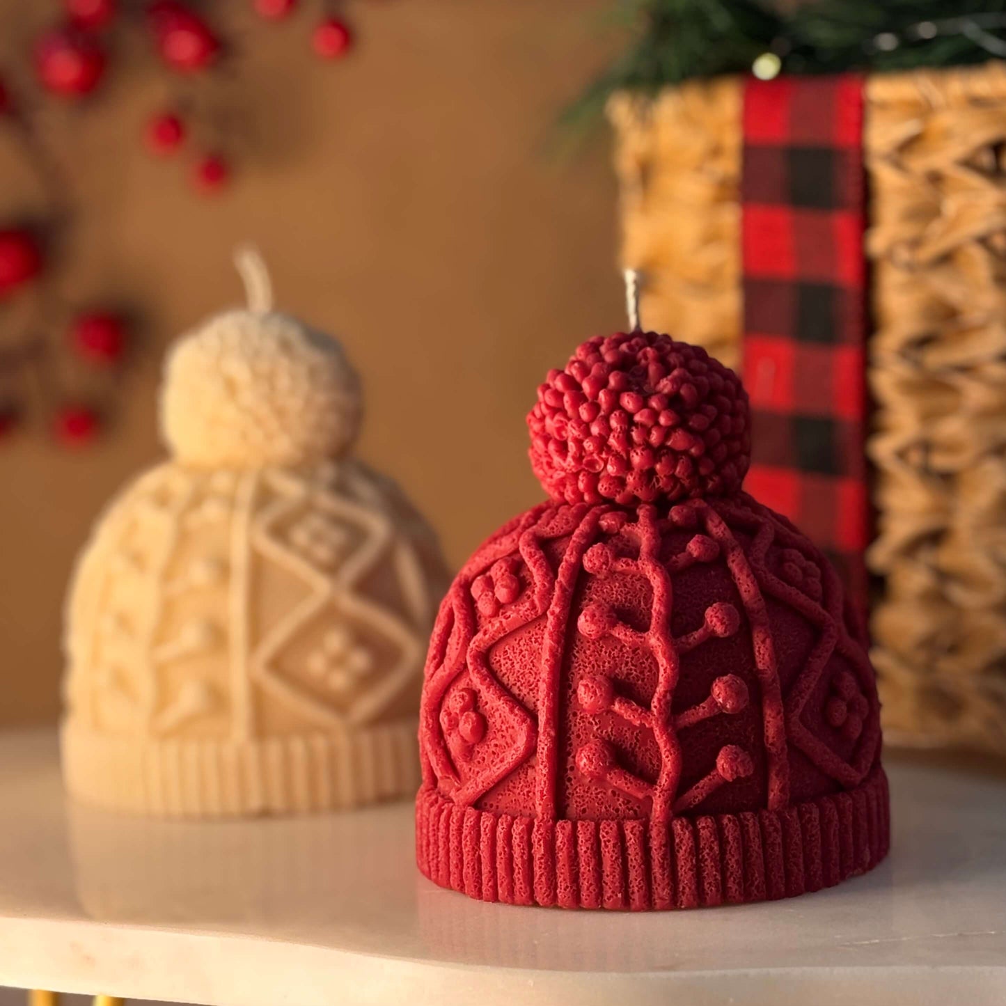 Red and cream knit hat candles styled as Secret Santa gift ideas on a festive table with holiday basket and soft lighting