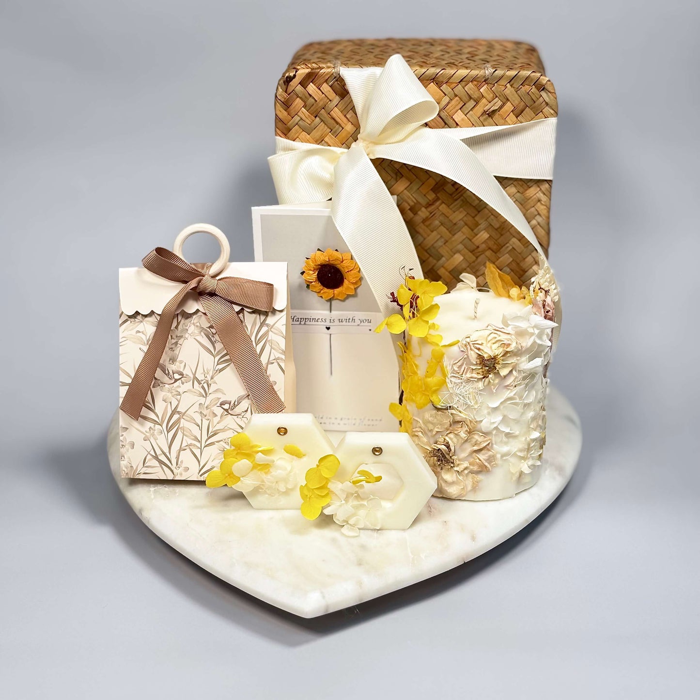Aesthetic gift box in yellow and white tones with handmade soy candle, floral wax sachets, and sunflower card on a heart-shaped tray
