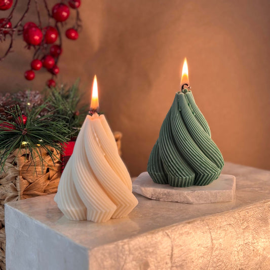 Two twisted Christmas tree-shaped soy candles in ivory and green colors with festive background and holiday decor

