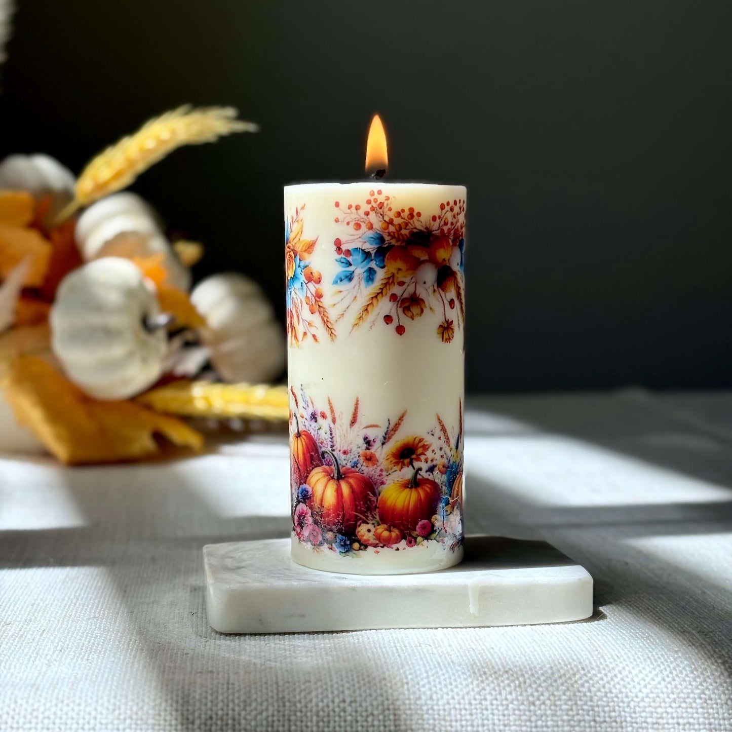 Autumn pumpkin candle glowing with holiday floral details, cozy fall home decoration, handmade candle for Thanksgiving and holiday décor.