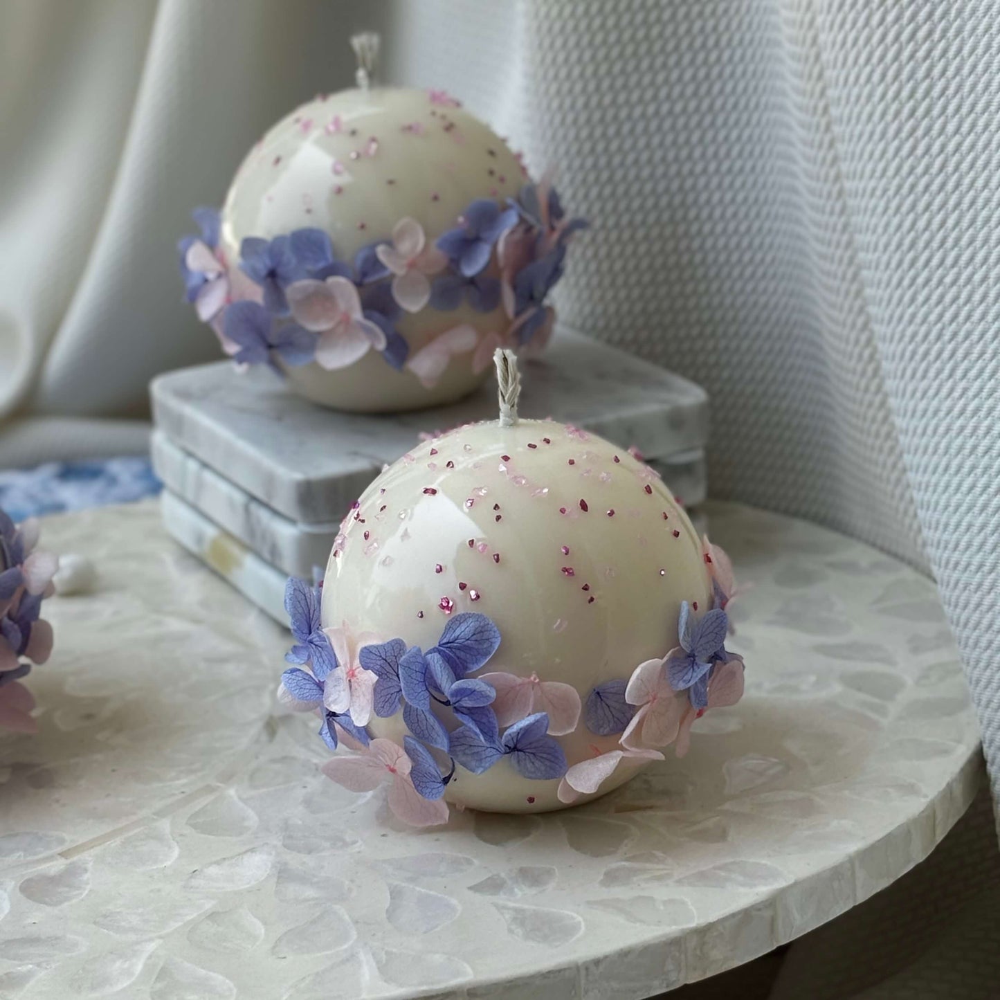 Pair of Bloomella round flower candles styled on mosaic side table for elegant home décor inspiration.	