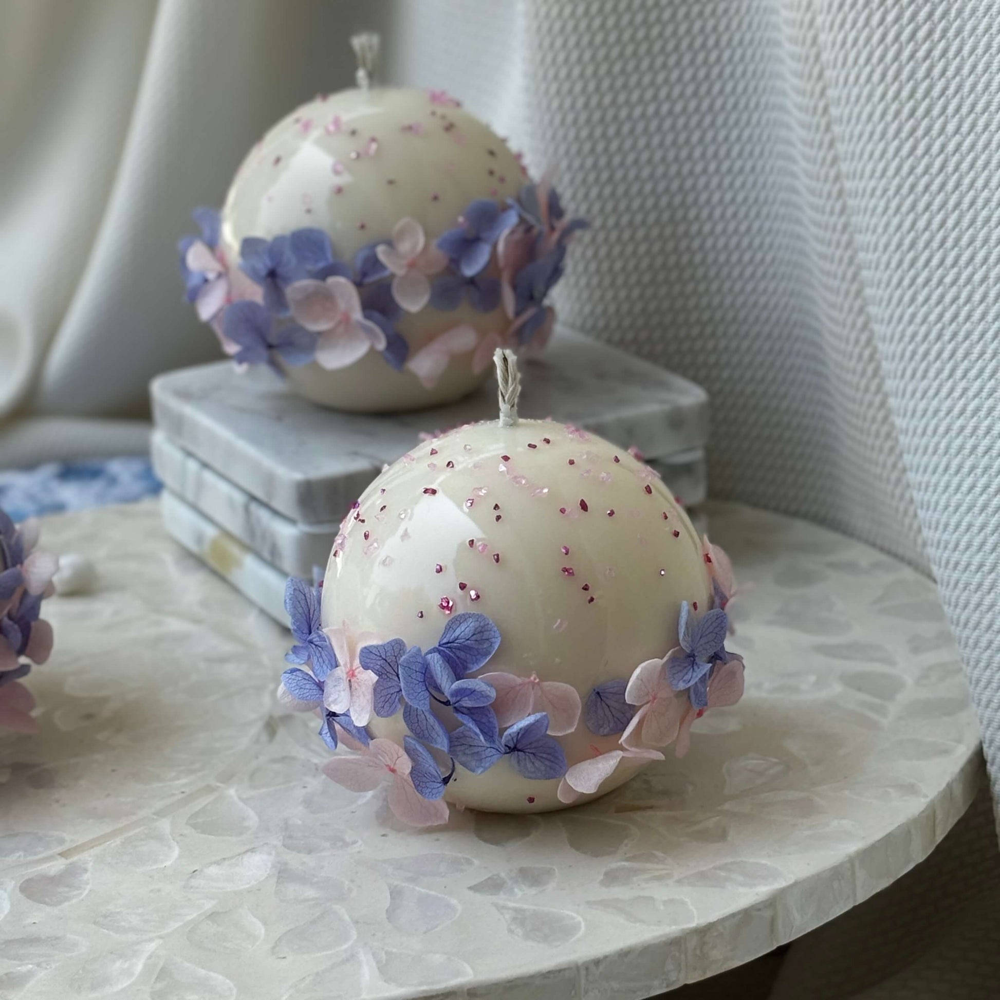 Pair of Bloomella round flower candles styled on mosaic side table for elegant home décor inspiration.	