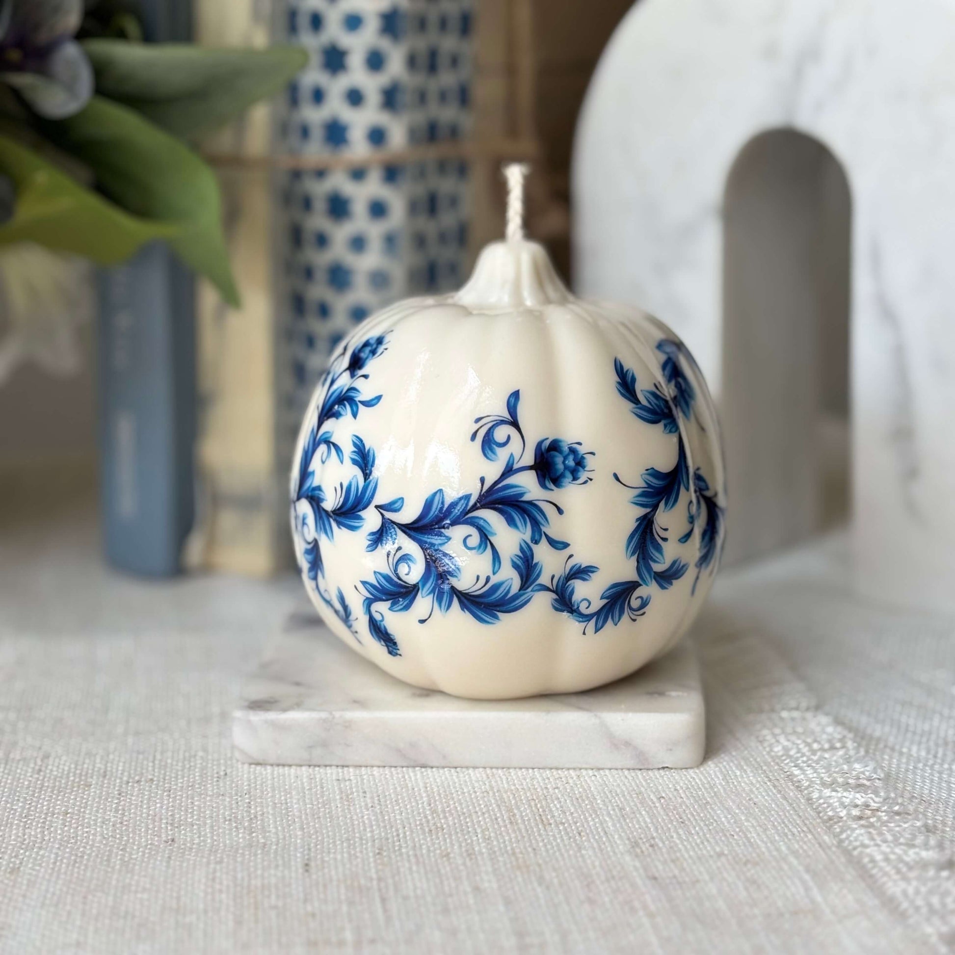 Handcrafted white pumpkin candle with blue vintage floral print, perfect for fall decor and Thanksgiving-inspired styling.

