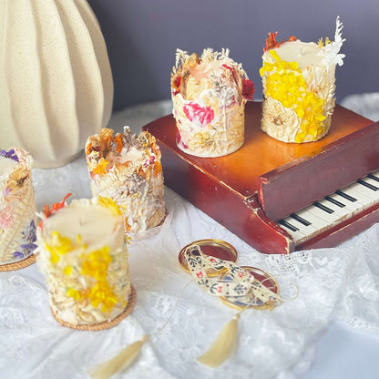 Vintage-style arrangement of handmade botanical soy candles with dried flowers in yellow, red, and purple accents — artisan decor and perfect gift idea.