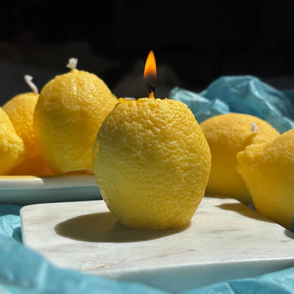Close-up of burning lemon candle made of soy wax. Realistic fruit candle shown lit for display.