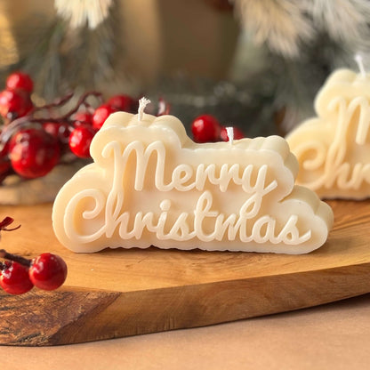holiday candle with merry christmas text on wood board with berries