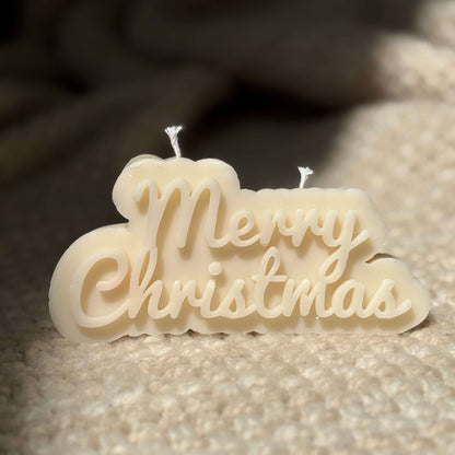 soy wax candle with merry christmas text placed on soft fabric for cozy winter gift ideas