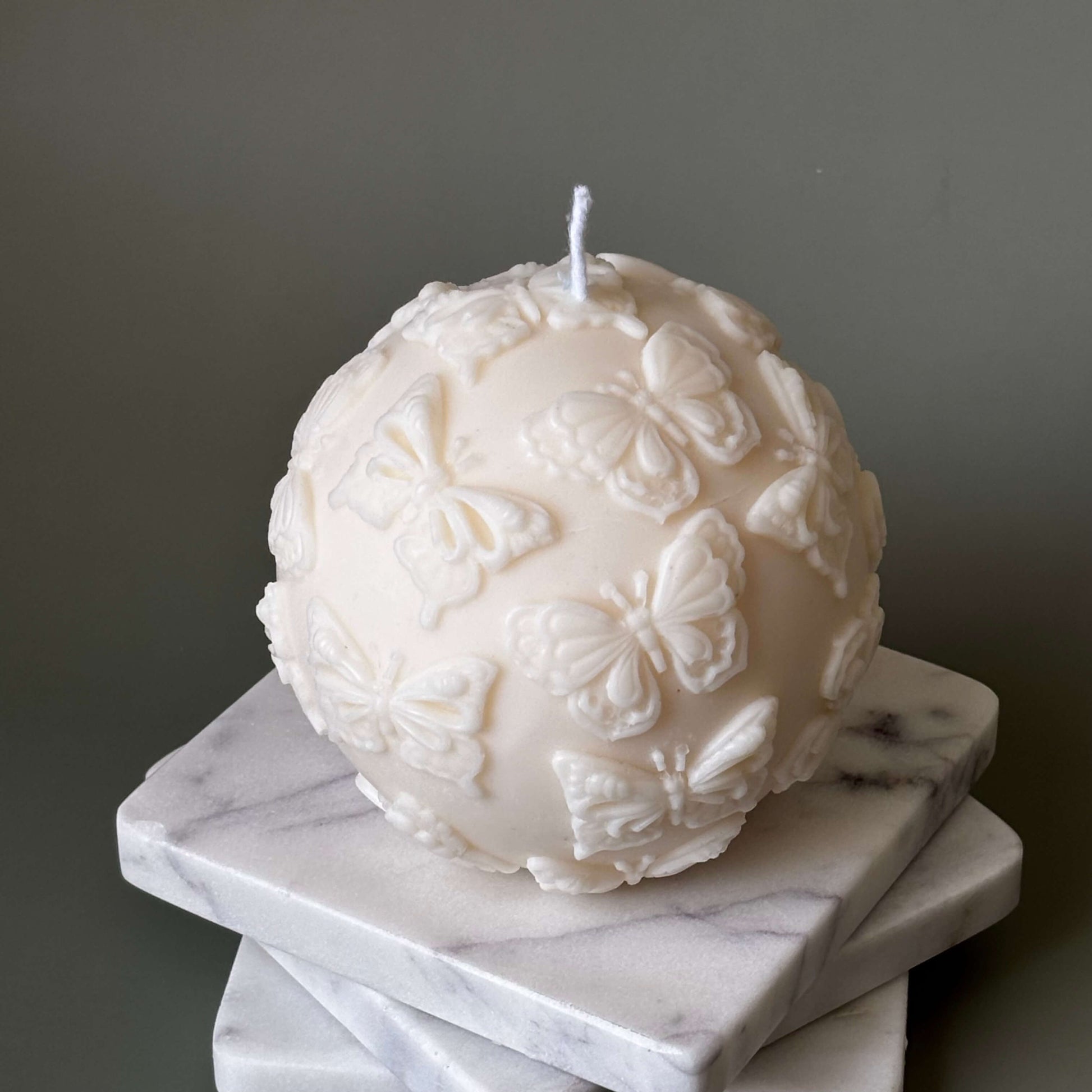 Decorative ball candle with butterfly texture on neutral background
