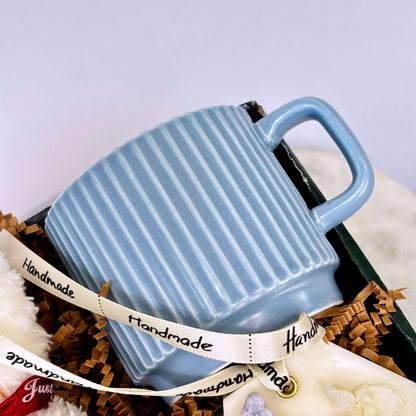 Close-up of ribbed ceramic mug nestled in gift box with shredded filler and handmade ribbon — ideal for cozy gifting, coffee lovers, and thoughtful care packages
