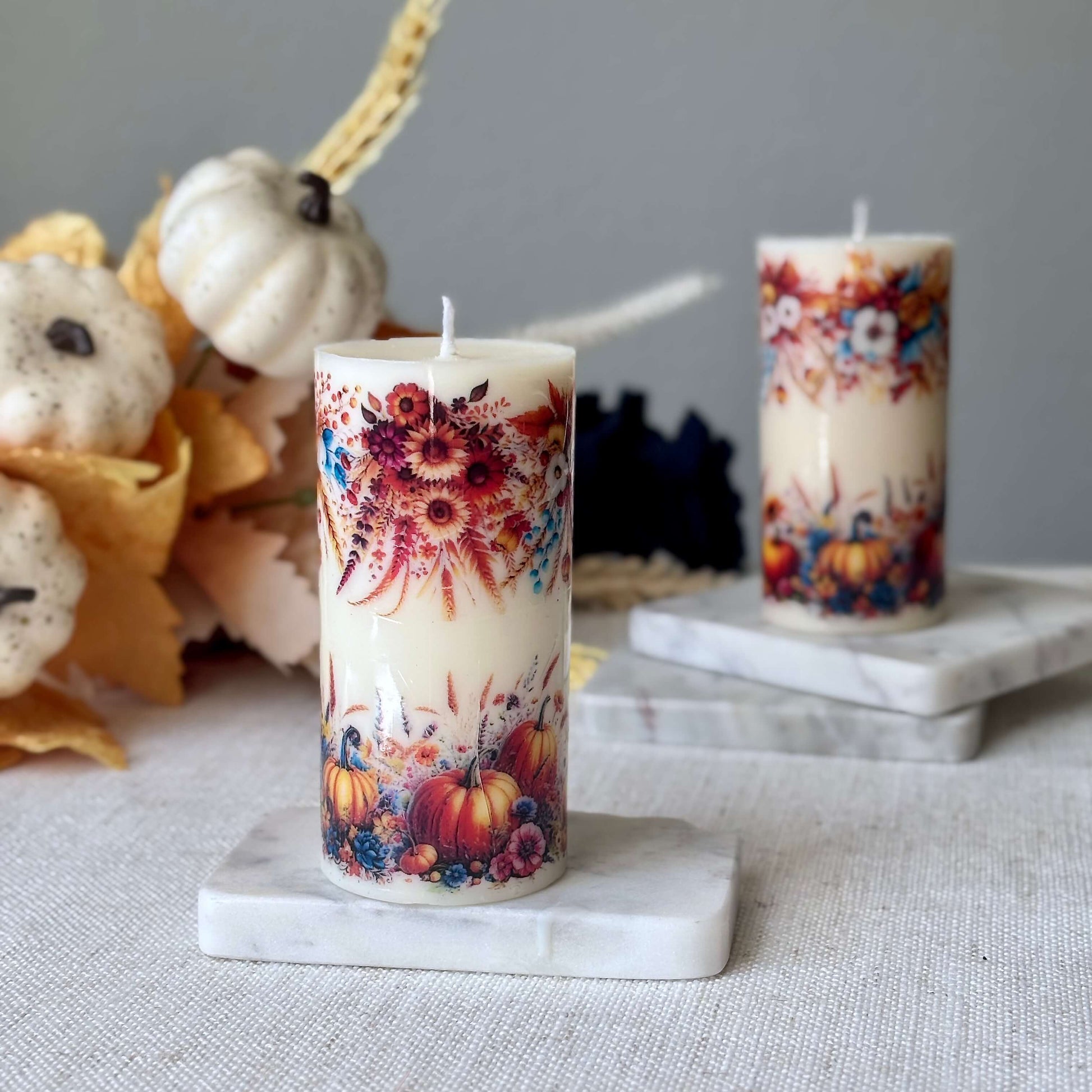 Pair of decorative pumpkin holiday candles with autumn flowers, seasonal fall decor accents for Thanksgiving dinner and holiday celebrations.