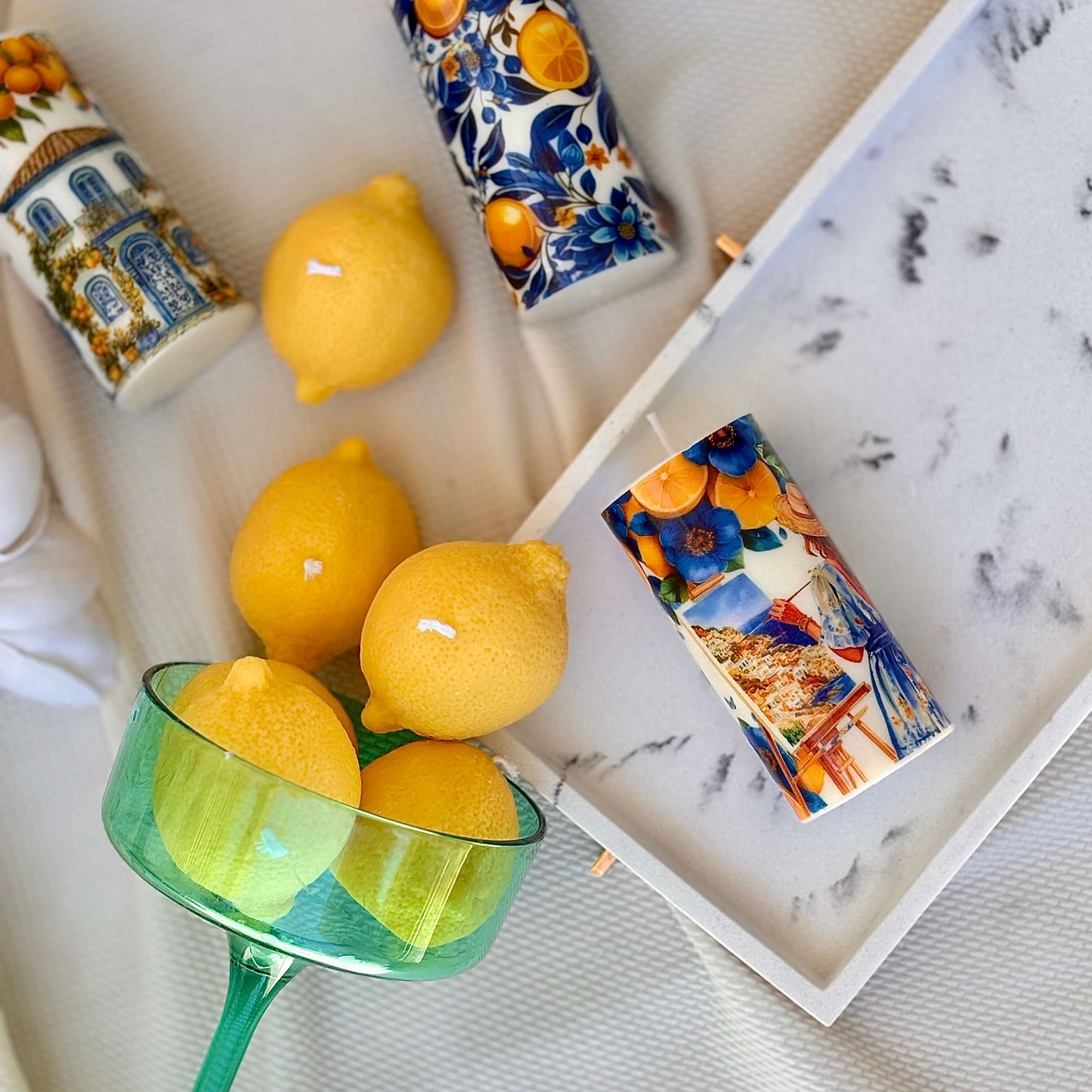 Flatlay of handmade Italian lemon candles with Mediterranean decor and green glass bowl


