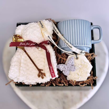 Flatlay of premium gift box with a soft teddy towel, ribbed ceramic mug, golden spoon, and handmade floral wax sachet — ideal for birthday gifts, self-care moments, or thank-you surprises