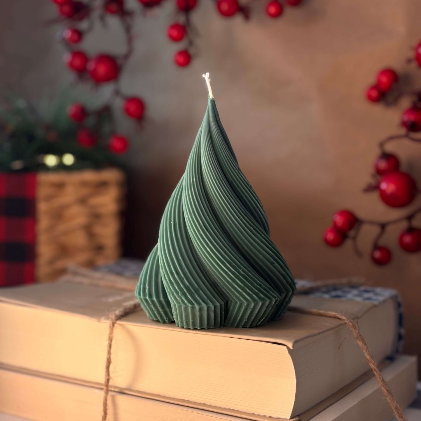 Green twisted candle in Christmas tree shape on stack of books, perfect Thanksgiving decor or cozy gift for mom

