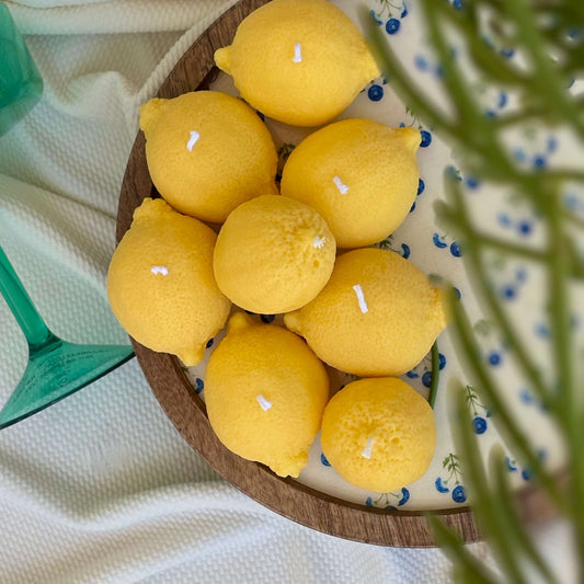 Handmade lemon candles in a wooden bowl. Fruit-shaped soy wax decor ideal for summer centerpiece.