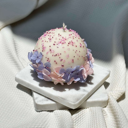 Luxurious handmade round candle with delicate flower details on elegant white marble tray