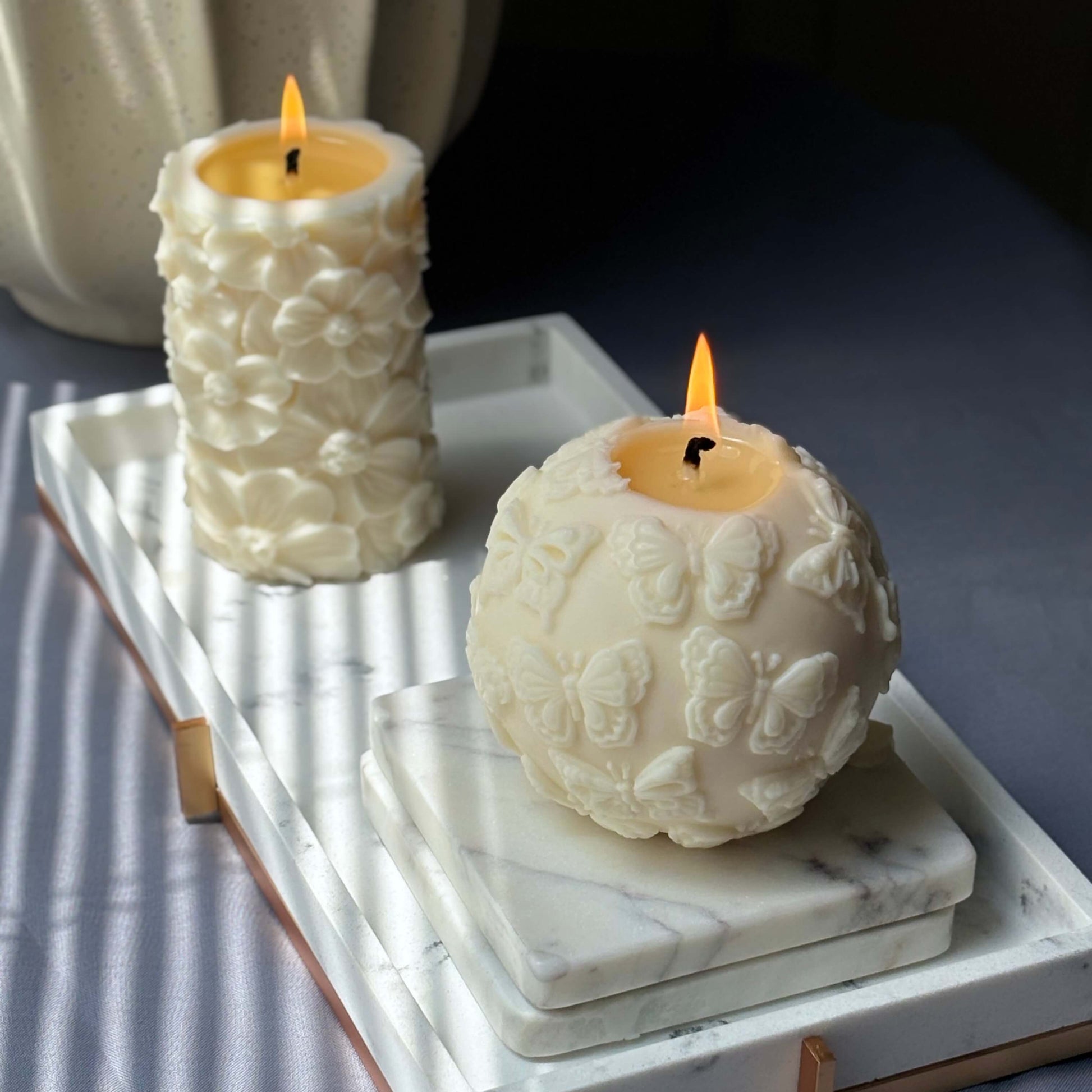 Modern sculpted candle with butterflies on stacked marble coasters
