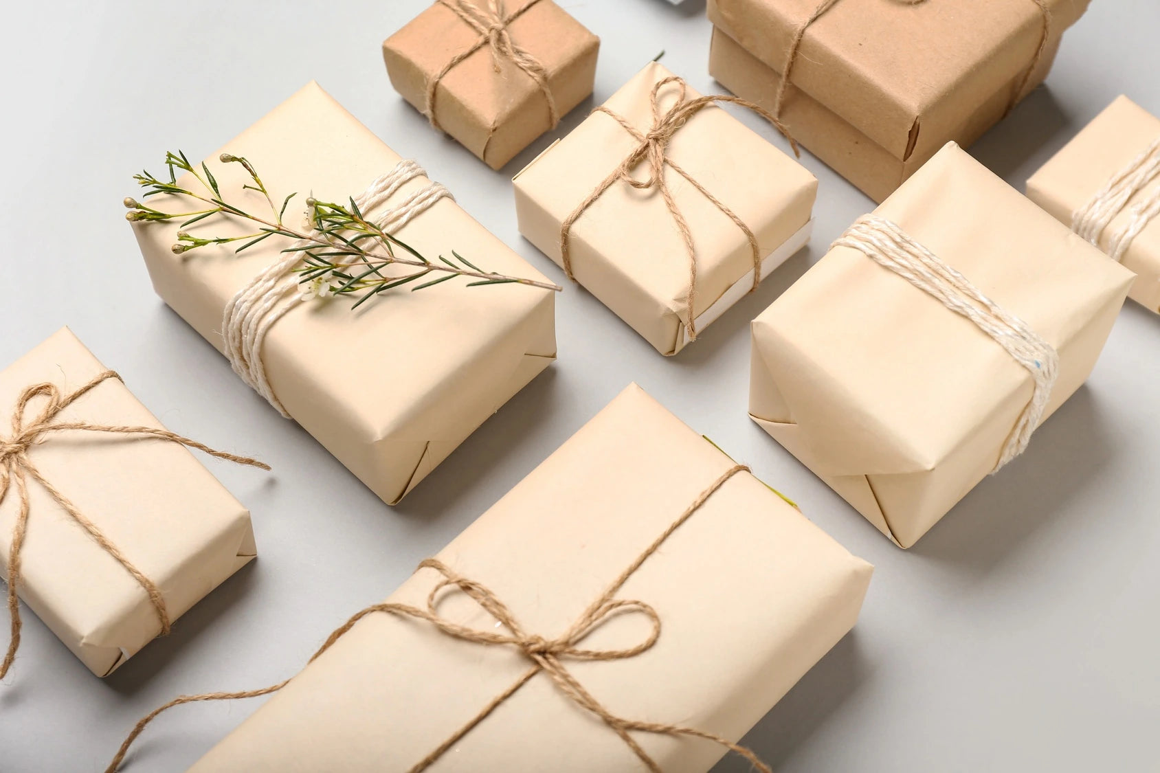 Aesthetic gift boxes wrapped in neutral craft paper with twine and greenery, styled for minimalist gifting