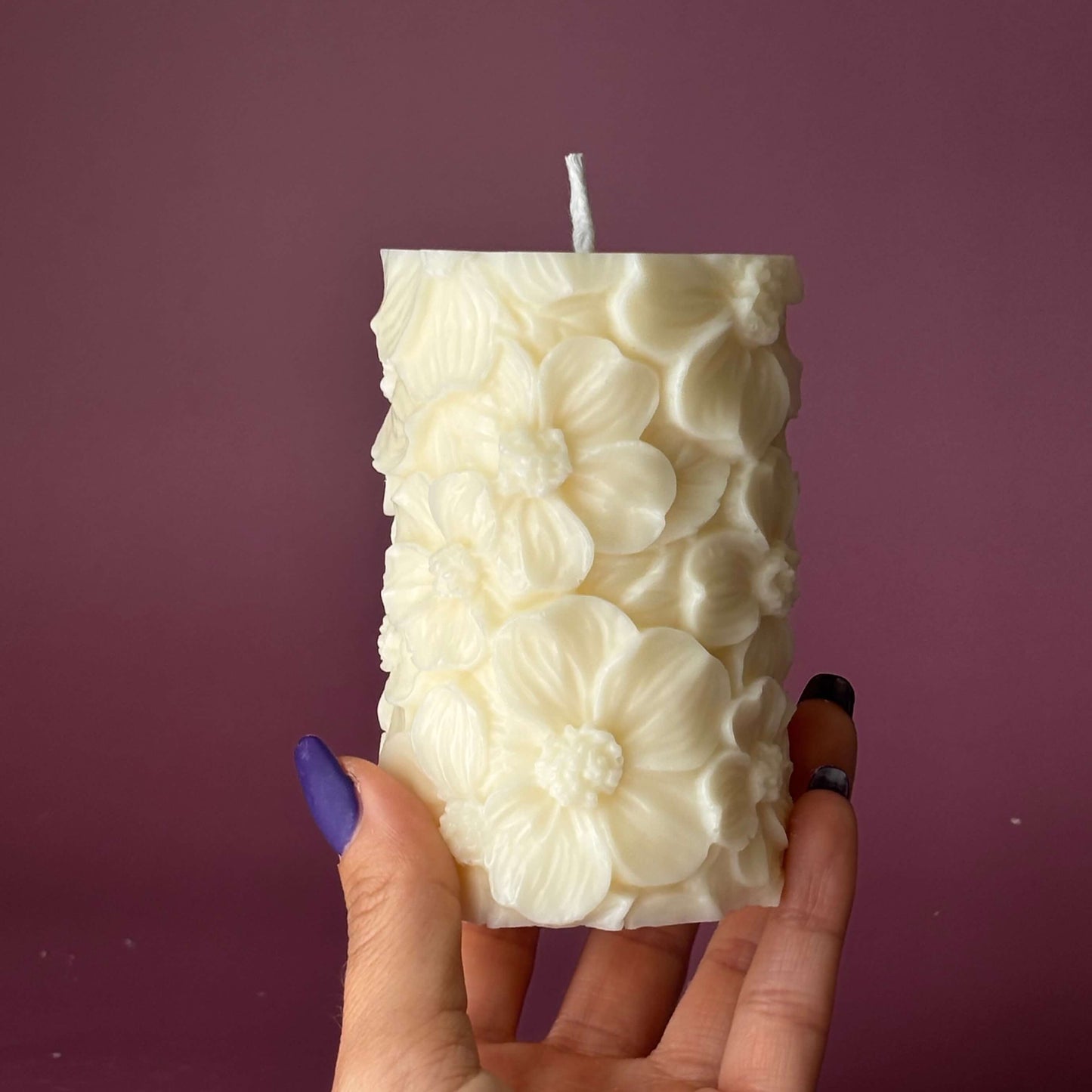 Hand holding handmade floral soy pillar candle – size reference	